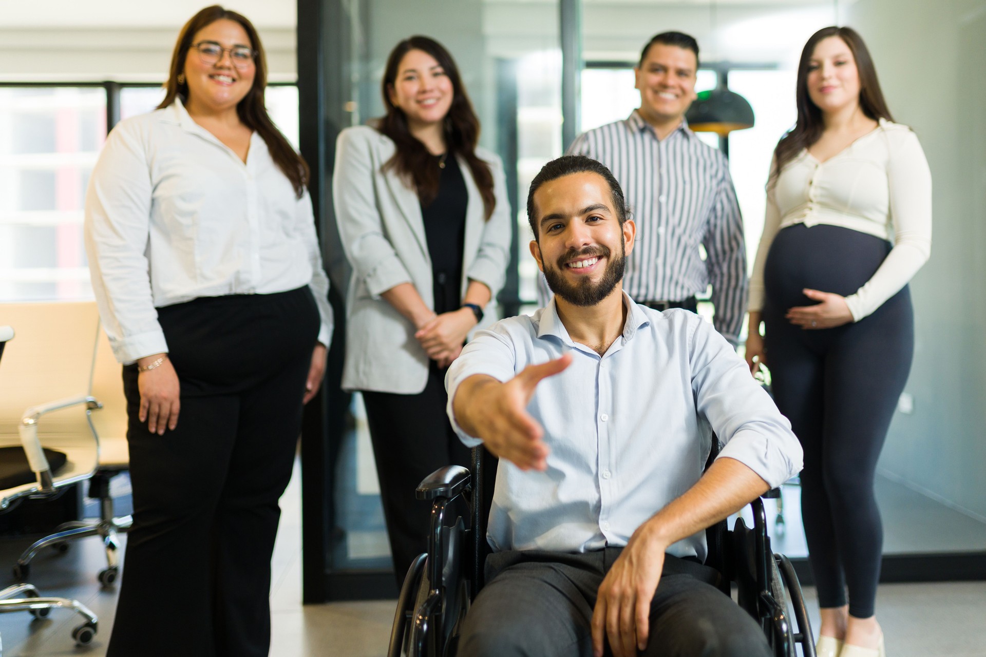 Disabled manager offering a handshake with his team at back in office